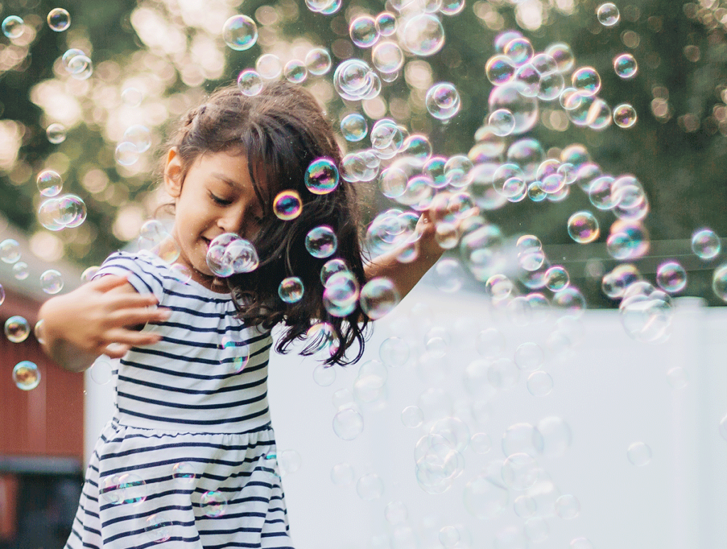 Une jeune fille s'amuse au milieu des bulles dans un mariage, photographiée par Laurent Agier